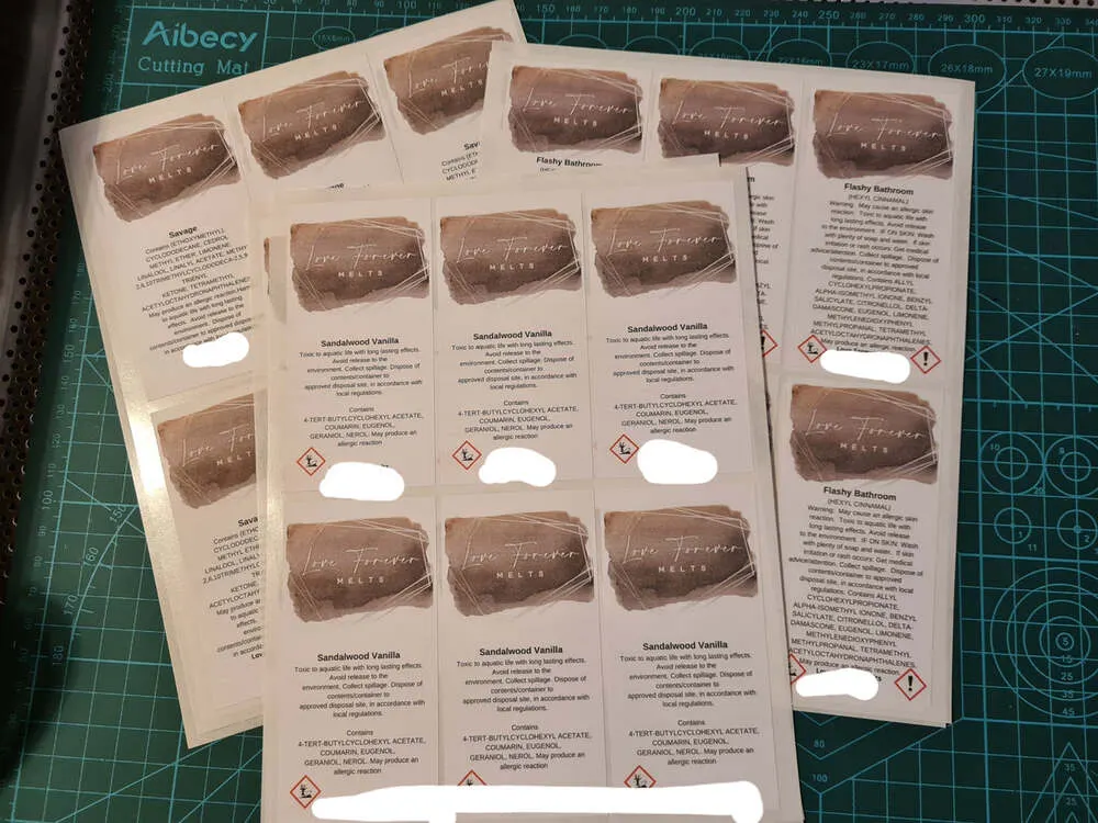 Sheets of rectangular CLP labels for clamshell wax melts on a cutting mat